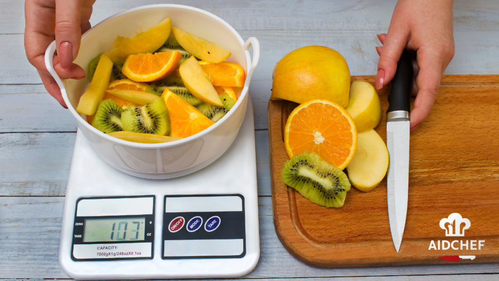 Báscula digital de cocina pesando frutas cortadas junto a cuchillo y tabla de madera
