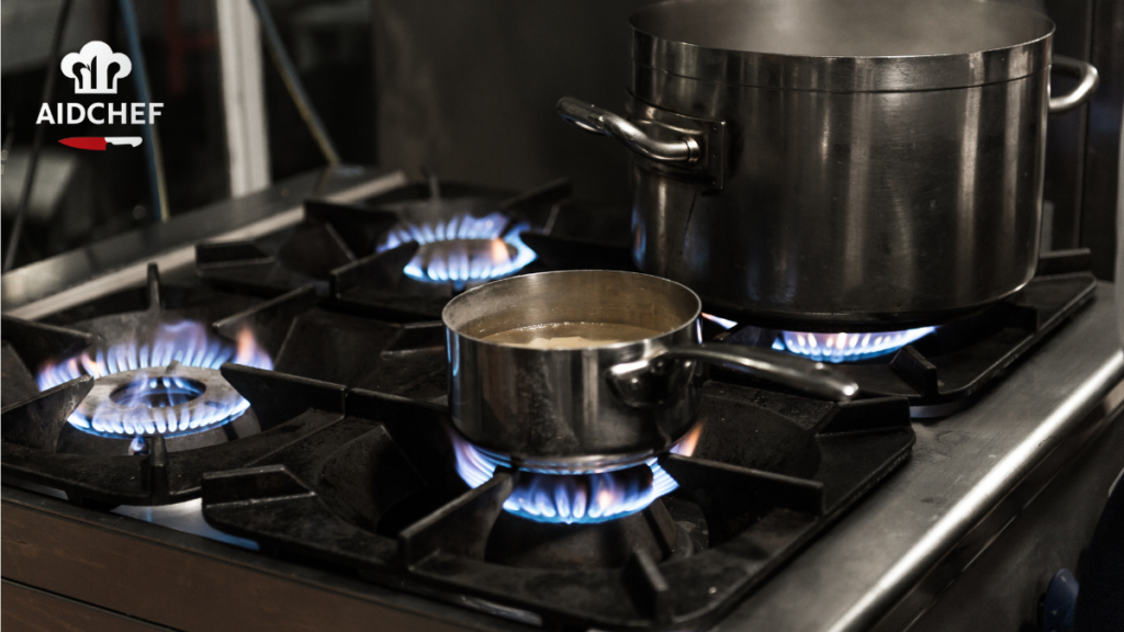 Cazo y olla de acero inoxidable cocinando sobre fogones de gas con llama azul