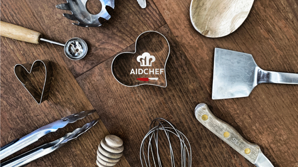 Utensilios de cocina esenciales sobre mesa de madera: espátula, varillas, pinzas y moldes