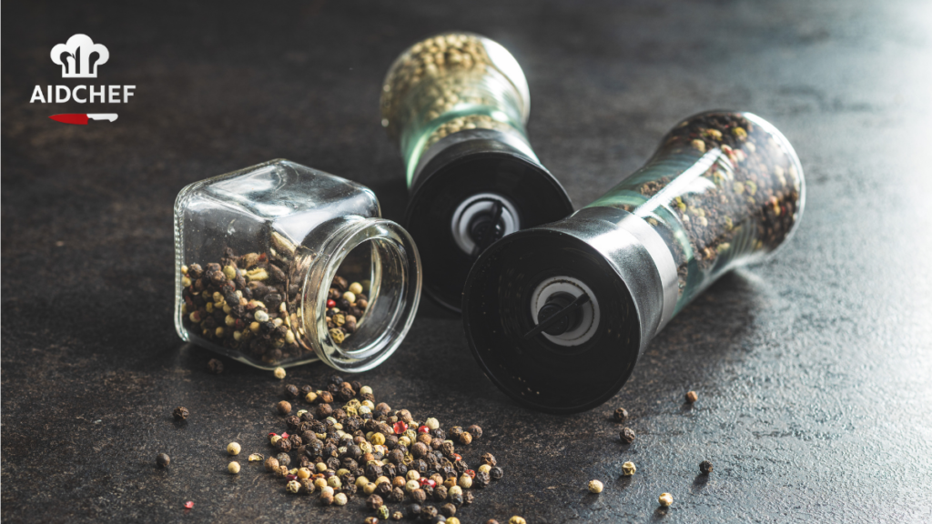 Molinillos de pimienta y especias con granos mezclados sobre superficie oscura